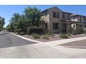 Street view of a two-story home with well-maintained desert landscaping and mature trees at 21013 W Wycliff Dr, Buckeye, AZ 85396