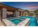 Beautiful pool and spa with outdoor kitchen, bar, and accent lighting, perfect for entertaining at 21275 E Russet Rd, Queen Creek, AZ 85142