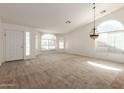 Bright, open living room with arched windows, neutral carpet, and a unique chandelier fixture at 3646 E Rousay Dr, San Tan Valley, AZ 85140