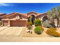 A tan single-story home featuring a tile roof, an arched entryway, a two-car garage, and desert landscaping at 4410 E Robin Ln, Phoenix, AZ 85050