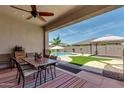 Covered patio with outdoor dining area, view of the swimming pool, and a well-maintained backyard space at 682 W Gum Tree Ave, Queen Creek, AZ 85140