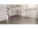 Spacious living room with light gray walls, wood-look floors, ceiling fan, and multiple archways at 10735 E Kilarea Ave, Mesa, AZ 85209