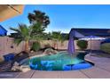 Backyard showcasing a captivating pool, rock waterfall, and lush tropical landscaping at 1085 E Oakland Ct, Gilbert, AZ 85295