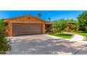 Brick home featuring a spacious two-car garage and a beautifully landscaped front yard at 125 E Loma Ln, Phoenix, AZ 85020