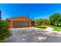 Brick home featuring a spacious two-car garage and a beautifully landscaped front yard at 125 E Loma Ln, Phoenix, AZ 85020