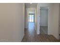 Bright hallway with wood-look tile flooring leading to a room with a sliding glass door at 18240 W La Senda Dr, Surprise, AZ 85387