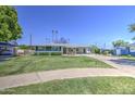 Charming single-story home with a well-manicured lawn and inviting curb appeal set under a clear blue sky at 1917 W Ashland Ave, Phoenix, AZ 85009