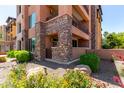 Close-up of condo's stone exterior, framed by beautiful landscaping with flowers and greenery at 4803 N Woodmere Fairway -- # 1002, Scottsdale, AZ 85251