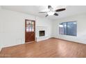 Bright living room features a brick fireplace, wood floors and a modern ceiling fan at 9641 N 36Th Dr, Phoenix, AZ 85051