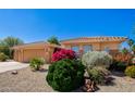 Single Gathering house with desert landscaping, flowering bushes, and a three-car garage at 16972 W Anasazi Ct, Surprise, AZ 85387