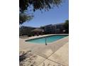 Community pool area with inviting turquoise water, bordered by a well-maintained concrete deck and shade structures at 2301 E University Dr # 280, Mesa, AZ 85213