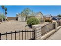 View of the front yard featuring desert landscaping, a metal fence and a mature tree at 6804 W Turquoise Ave, Peoria, AZ 85345