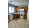 Bright kitchen with tile flooring, wood cabinetry, white appliances, and ample counter space at 12138 W Flores Dr, El Mirage, AZ 85335