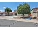 A well-kept two-story home featuring desert landscaping, mature trees, and a wide driveway at 15040 W Windrose Dr, Surprise, AZ 85379