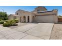 Spacious single-Gathering home showcasing an arched porch, 3-car garage, desert landscaping, and solar panels at 16118 W Port Au Prince Ln, Surprise, AZ 85379