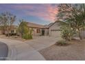 Charming home exterior with a circular driveway and desert landscaping under a lovely sunset sky at 18199 W Buckhorn Dr, Goodyear, AZ 85338