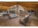 Covered outdoor lounge area with comfortable seating, stone fireplace, and wood beams at 25424 N 176Th Ave, Surprise, AZ 85387