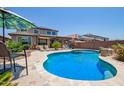 Resort-style pool with desert landscaping, patio umbrellas, lounge seating, and solar panels on the roof at 25546 N 164Th Dr, Surprise, AZ 85387