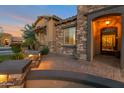 Close up of the front entrance shows decorative stone and iron door, plus pavers and landscaped features with outdoor lighting at 3907 E Carob Dr, Gilbert, AZ 85298