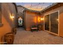Cozy patio features rustic decor, string lights, and access to the home through a sliding glass door and decorative iron gate at 3907 E Carob Dr, Gilbert, AZ 85298