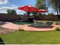 Relaxing backyard featuring a private pool, rock waterfall, and well-manicured lawn at 45722 W Barbara Ln, Maricopa, AZ 85139