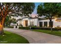Beautiful home showcasing a well-maintained lawn, manicured landscaping, and black framed windows at 5700 E Sanna St, Paradise Valley, AZ 85253
