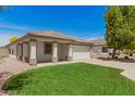 Inviting single-story home with lush green lawn, a two-car garage, and a charming covered porch at 10212 E Caballero St, Mesa, AZ 85207
