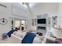 Bright living room with vaulted ceilings, built-in shelving, a fireplace, and glass doors leading to an outdoor space at 3038 E Stella Ln, Phoenix, AZ 85016