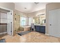 Luxurious bathroom features a soaking tub, glass shower, dual vanities, and travertine tile at 3177 S Sierra St, Gilbert, AZ 85295