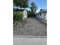 Gravel driveway between two buildings with mature landscaping and a brick-lined edge at 3639 W Beryl Ave, Phoenix, AZ 85051