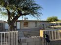 Exterior view of a cozy single story home with a big tree and a small patio area and low fence at 3946 W Holly St, Phoenix, AZ 85009