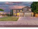 Beautiful home showcasing a well-maintained lawn, desert landscape, and wide driveway to the three-car garage at 6961 W Honeysuckle Dr, Peoria, AZ 85383