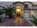 Inviting home featuring a grand archway entrance, desert landscaping, and path lighting at 13636 W Calavar Rd, Surprise, AZ 85379