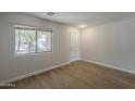Bright, empty room featuring wood floors, a window overlooking mature tree and a white door at 1671 E Silktassel Trl, San Tan Valley, AZ 85143