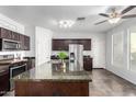 Stylish kitchen showcasing dark wood cabinetry, granite counters, and a large center island with a sink at 21014 W Ridge Rd, Buckeye, AZ 85396