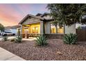 Charming single-story home with desert landscaping and a cozy front porch at sunset at 21022 E Arroyo Verde Ct, Queen Creek, AZ 85142