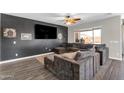 Cozy living room featuring a large sectional couch, ceiling fan, and access to the backyard at 23886 W Harrison Dr, Buckeye, AZ 85326