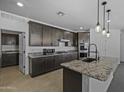 Well-equipped kitchen featuring dark cabinetry, granite counters, a stylish faucet, and modern appliances for gourmet cooking at 36602 W San Alvarez Ave, Maricopa, AZ 85138