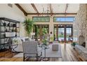 Bright living room featuring high, beamed ceilings, wood floors, a stone fireplace, and patio access at 41916 N 101St N Pl, Scottsdale, AZ 85262