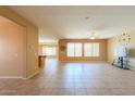 Spacious living room featuring tile floors, large windows, and seamless flow into the dining and kitchen areas at 42360 W Abbey Rd, Maricopa, AZ 85138