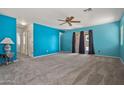 Large living room with neutral carpet, bright blue walls, and access to the backyard at 43938 W Colby Dr, Maricopa, AZ 85138