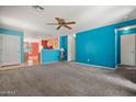Spacious living room with an open layout, neutral carpet, and bright wall colors at 43938 W Colby Dr, Maricopa, AZ 85138