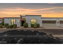 Charming townhome featuring white stucco, a red tile awning, a garage, and well-maintained landscaping at sunset at 5314 N Las Casitas Pl, Phoenix, AZ 85016