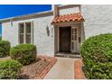 Close-up of a charming front entryway with a security door, a red tile awning, and lush landscaping at 5314 N Las Casitas Pl, Phoenix, AZ 85016