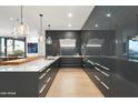 Sleek modern kitchen with white countertops, light wood floors, custom lighting, and gray cabinets at 7180 E Kierland Blvd # 1116, Scottsdale, AZ 85254