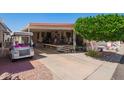 Charming home with covered porch, mature tree, and golf cart for convenient living at 8700 E University Dr # 1205, Mesa, AZ 85207