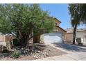 Two story home featuring a driveway, two car garage, desert landscaping with rock features, and a red tile roof at 12408 W Orange Dr, Litchfield Park, AZ 85340