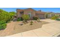 Single-Gathering home with desert landscaping, an iron gate, and a brick driveway leading to the garage at 14333 W Alvarado Dr, Goodyear, AZ 85395