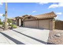 Wide driveway leads to a tan stucco home featuring a tile roof and a three-car garage at 1449 W Sherri Dr, Gilbert, AZ 85233