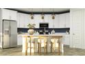 Modern kitchen featuring white cabinetry, a stainless steel refrigerator, and a center island with bar seating at 15883 W Winslow Ave, Goodyear, AZ 85338